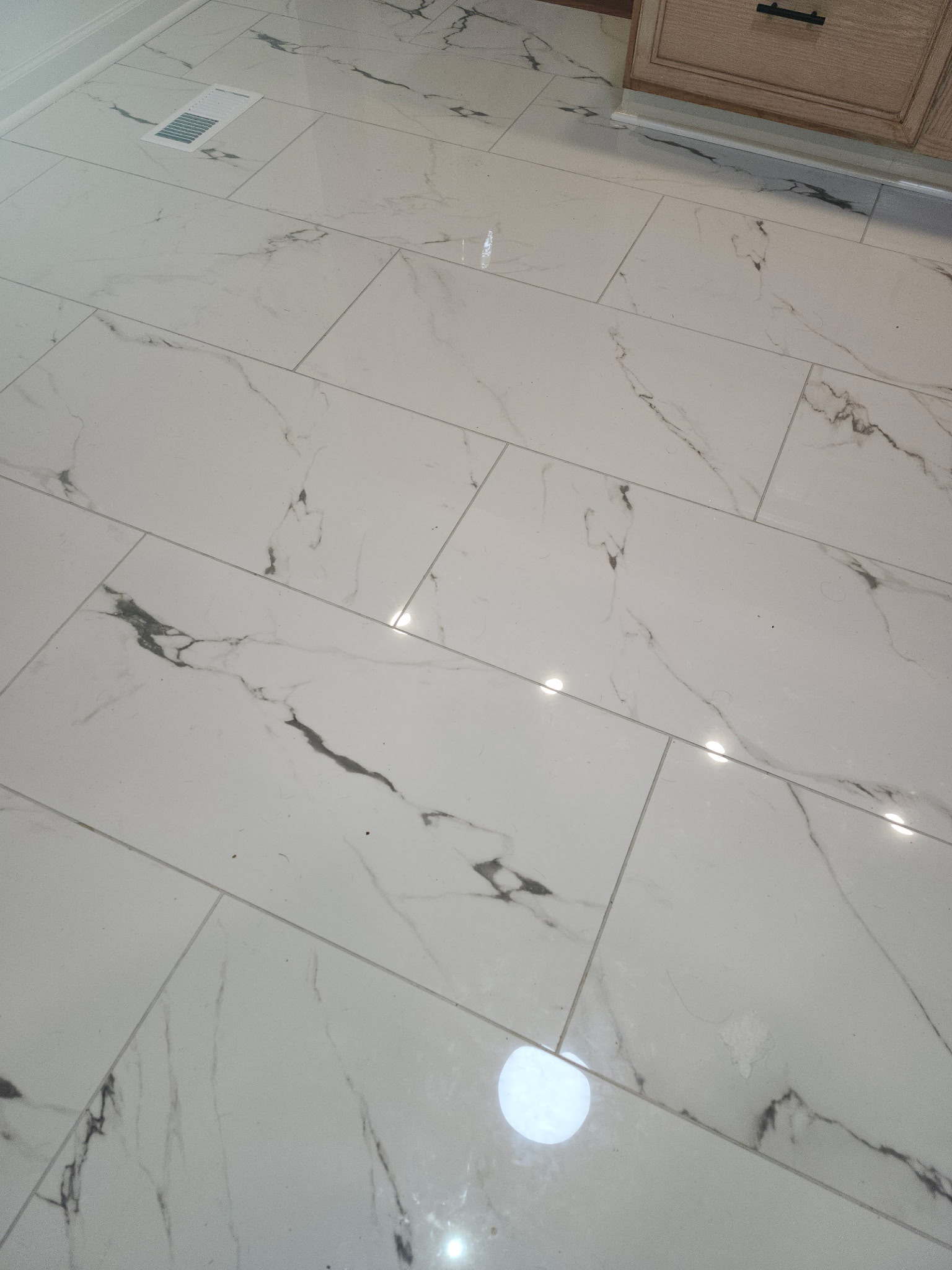 Marble-look porcelain tiles with gray veining installed in linear pattern during kitchen remodeling project.