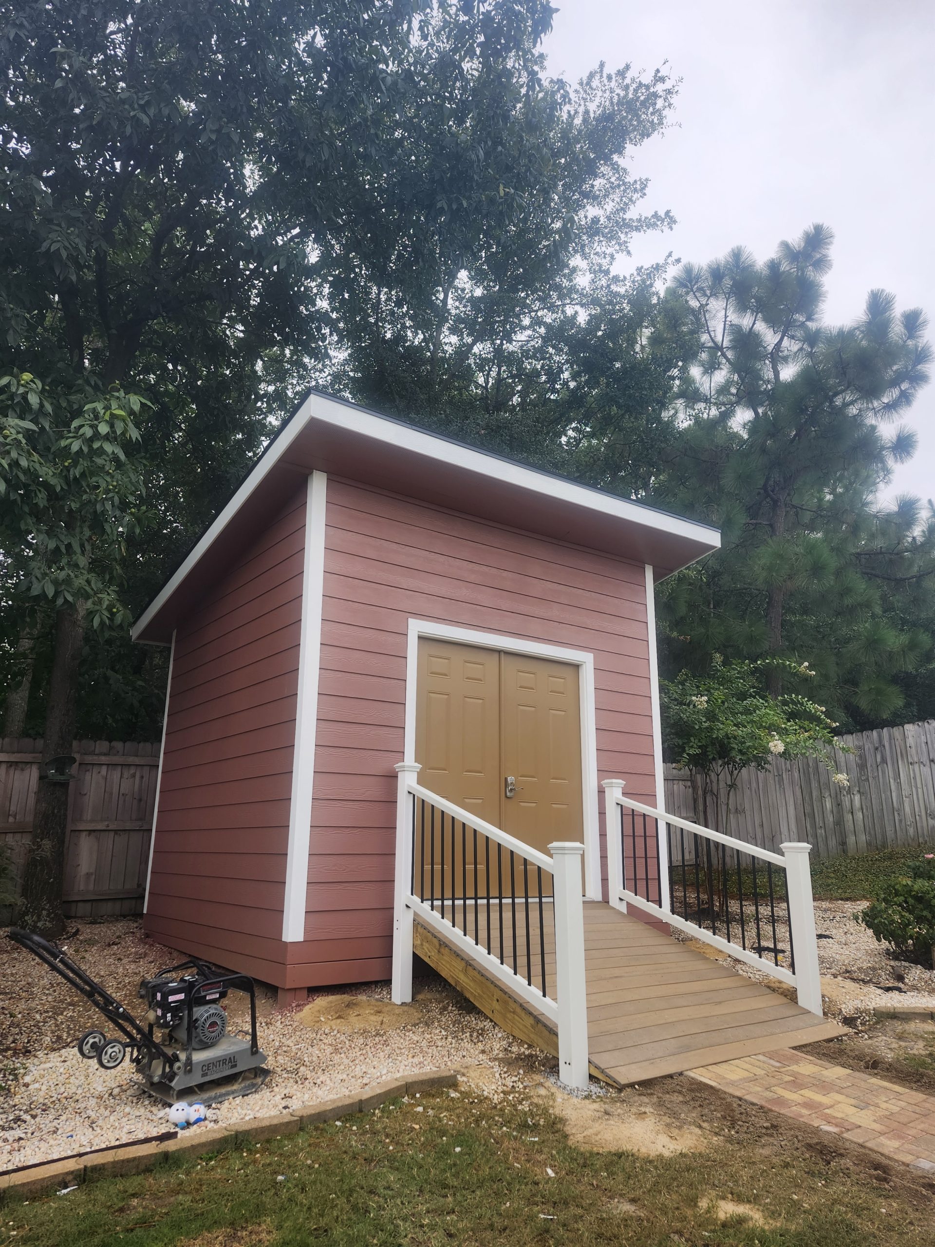 Custom backyard accessory dwelling with burgundy siding, white trim, and professional ramp installation in South Carolina.